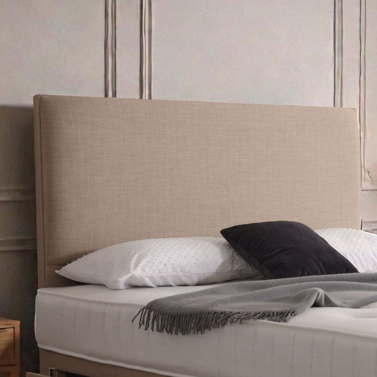 Softly padded Roman-style upholstered headboard with neutral fabric, designed for a comfortable and stylish bedroom setting.